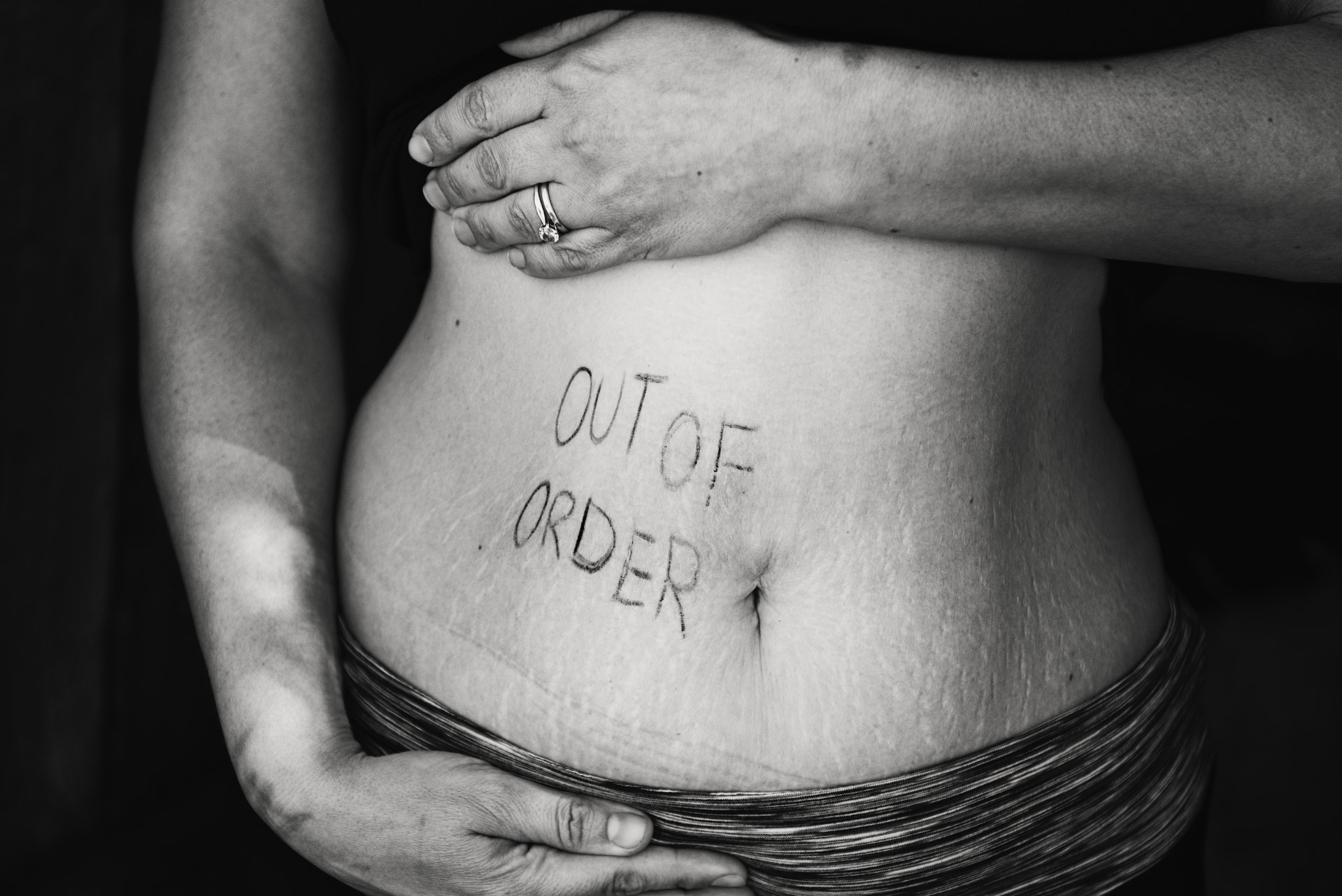 Womans stomach with 'out or order' written on it